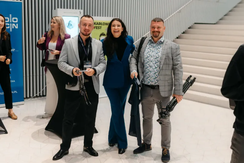 Radosław Zacha i Michał Olejarski z uśmiechniętą uczestniczką w foyer Filharmonii